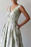 Uma linha de vestido floral verde-claro longo e franzido de mãe da noiva com bolsos